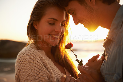 Buy stock photo Flower, sunset and young couple at beach on vacation, adventure or holiday for valentines day. Love, smile and man and woman with floral plant by ocean for tropical weekend trip on romantic date.