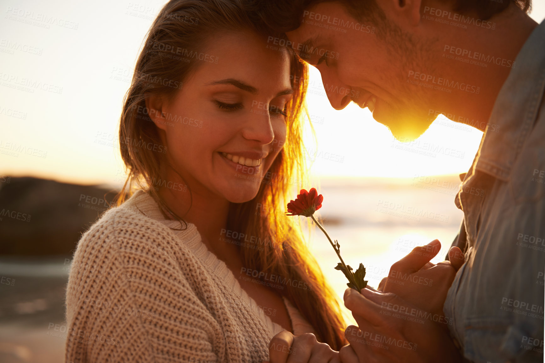 Buy stock photo Flower, sunset and young couple at beach on vacation, adventure or holiday for valentines day. Love, smile and man and woman with floral plant by ocean for tropical weekend trip on romantic date.