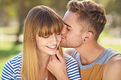 Buy stock photo Shot of  a young couple sharing a tender moment together while enjoying a day in the park