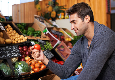 Buy stock photo Shot of a young man in a supermarket shopping for fresh produce