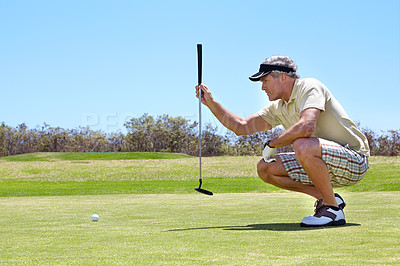 Buy stock photo Shot of a mature man lining up a putt on a green