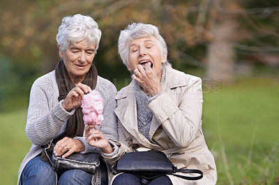 Buy stock photo Senior women, eating and hungry in nature with candy floss, together and relax on retirement in outdoor. Elderly friends, happy and junk food on vacation in countryside, bonding and social in park