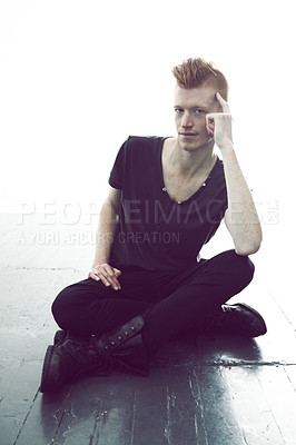 Buy stock photo Portrait, ginger and man sitting on a floor with hand on head or wearing black or in thought for fashion and against white wall. Mohawk, dark and young guy thinking in punk clothes or rock and roll

