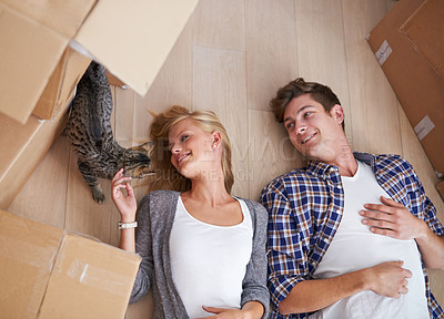 Buy stock photo Shot of a couple lying on the floor happily after a long day of moving house