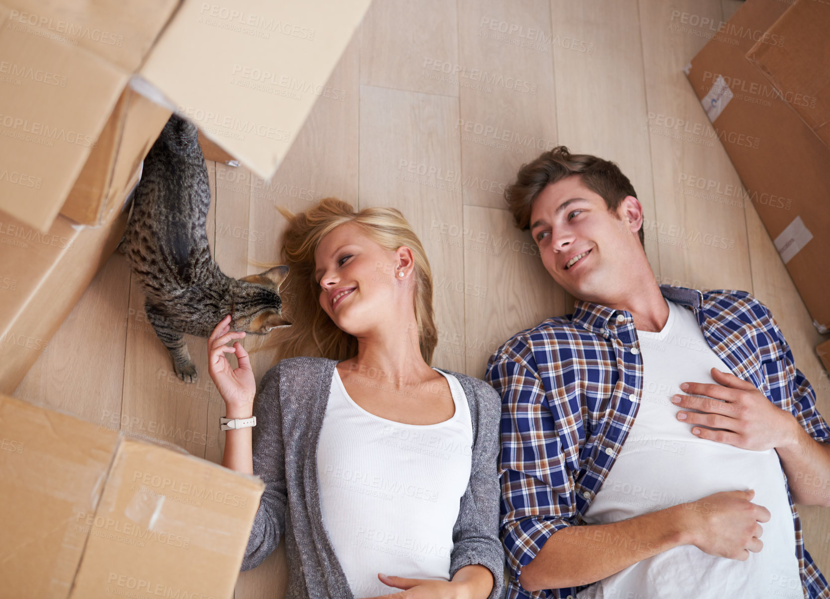 Buy stock photo Shot of a couple lying on the floor happily after a long day of moving house