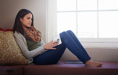Buy stock photo A young woman reading a book at home