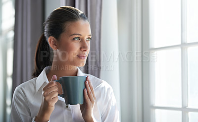Buy stock photo Shot of a young businesswoman enjoying a cup of coffee while standing next to a windown