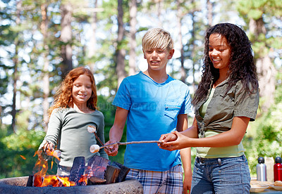 Buy stock photo Three kids standing outside roasting marshmallows over a fire
