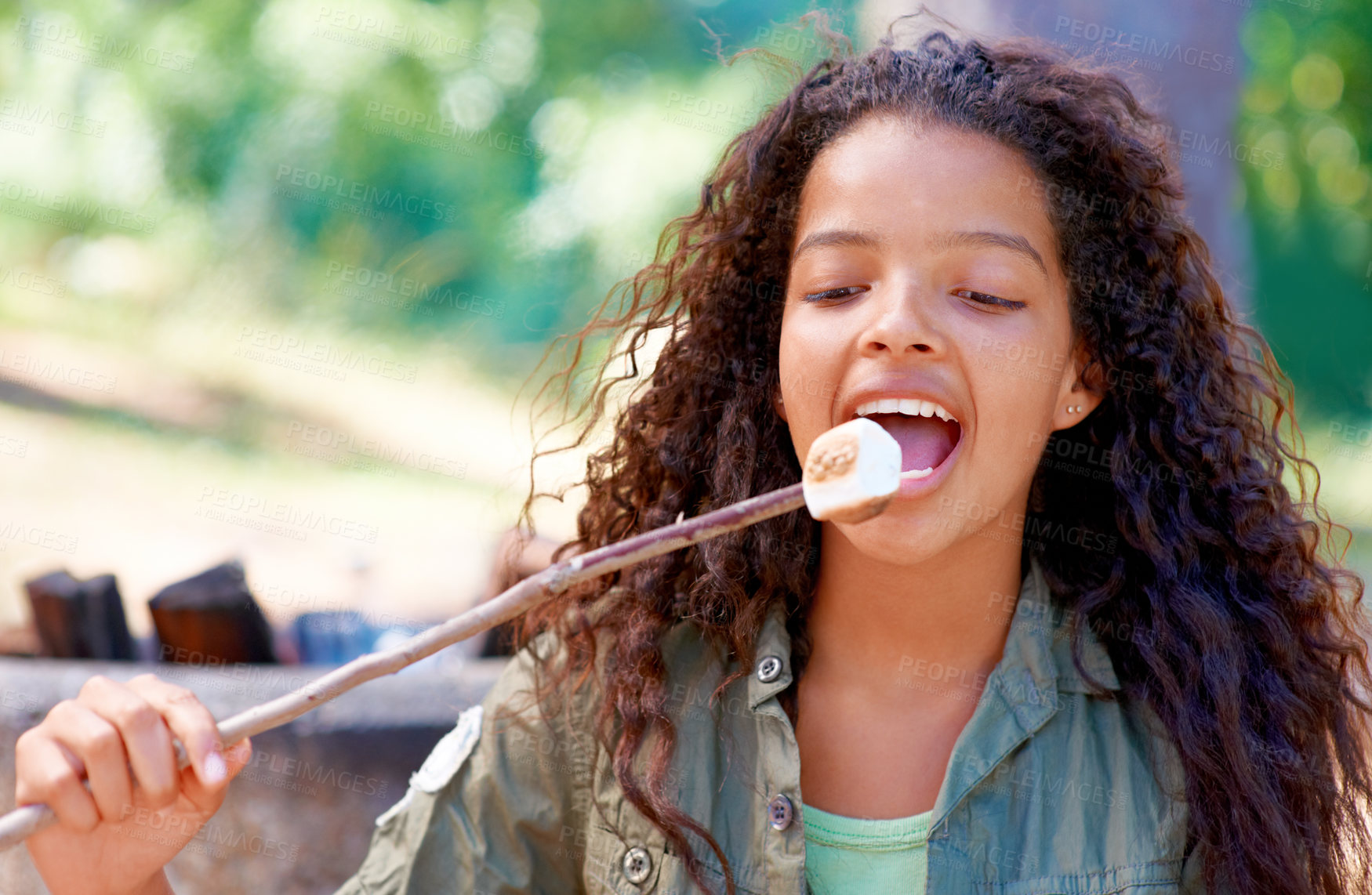 Buy stock photo A young girl biting a fireside treat