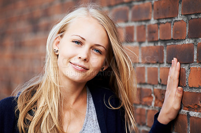 Buy stock photo Portrait of an attractive young woman leaning against a brick wall