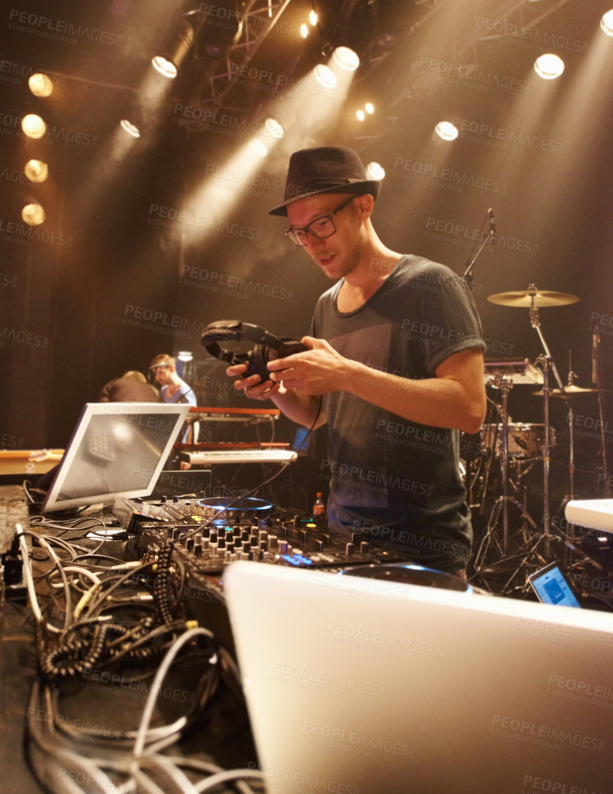 Buy stock photo Music, DJ and spotlight on man at stage with headphones and equipment for performance on sound board. Techno, musician and person in club at night mixing on turntable with technology for rave