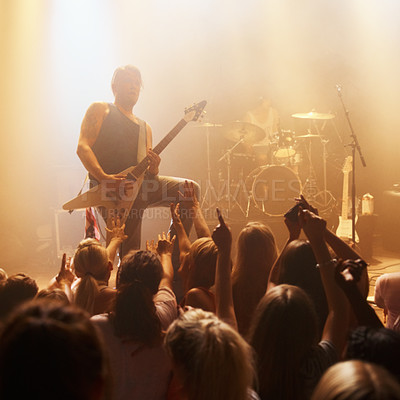 Buy stock photo Shot of a young guitarist performing a solo for the crowd at a music concert. This concert was created for the sole purpose of this photo shoot, featuring 300 models and 3 live bands. All people in this shoot are model released.
