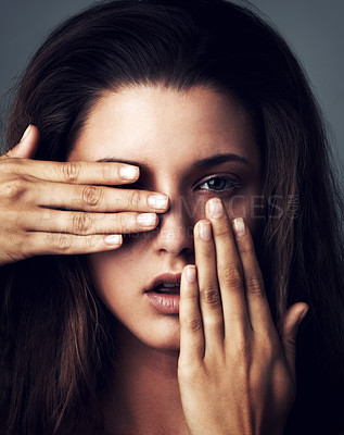 Buy stock photo Studio portrait of an attractive young woman posing with her hands covering her face against a grey background