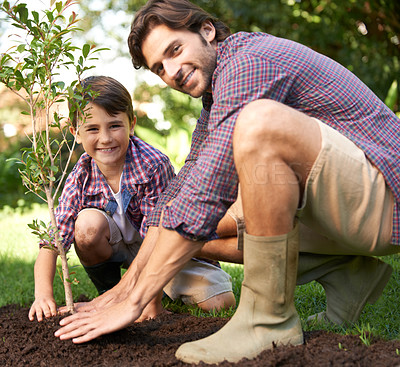 Buy stock photo Portrait, father and child planting a tree together for sustainability, gardening and ecology. Happy, family and a little boy helping dad plant trees in the garden for landscaping, hobby and bonding