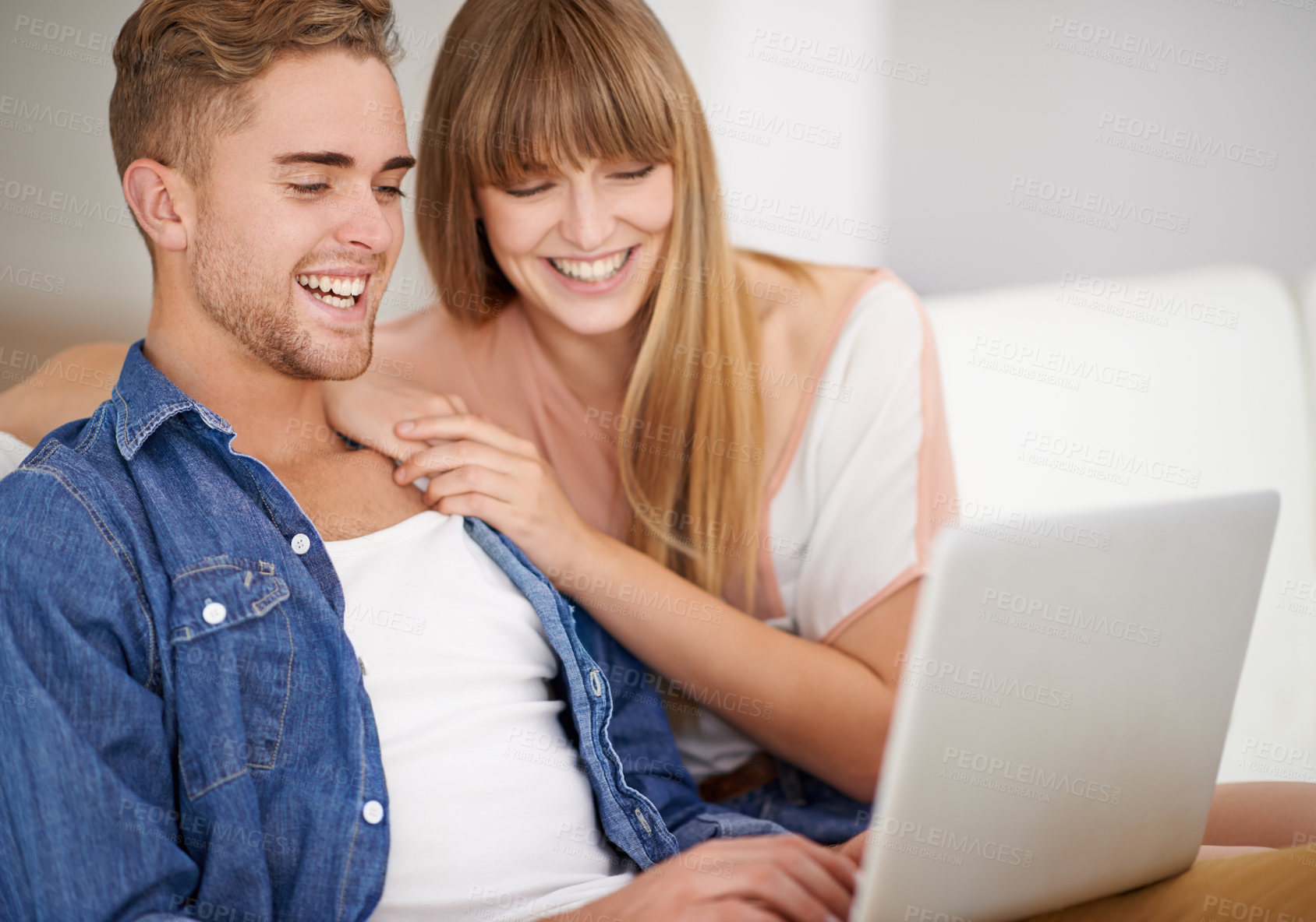 Buy stock photo A young couple using a laptop while relaxing on the couch