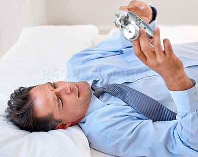 Buy stock photo Businessman, alarm clock and upset to wake up for work and schedule in the bed at home. Mature male person, clock and frustrated with watch for appointment and sleep or fatigue while lying in bedroom