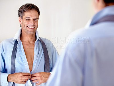 Buy stock photo A mature businessman looking at his reflection in the mirror while getting ready for work