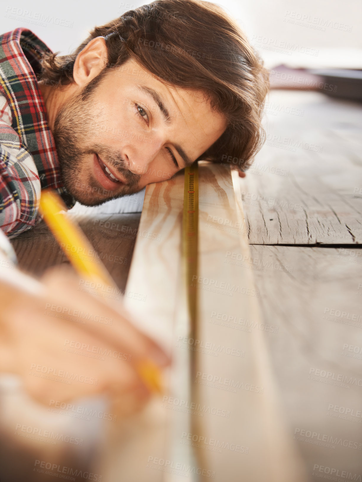 Buy stock photo A handsome young carpenter measuring and marking wood