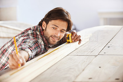 Buy stock photo A handsome young carpenter measuring and marking wood