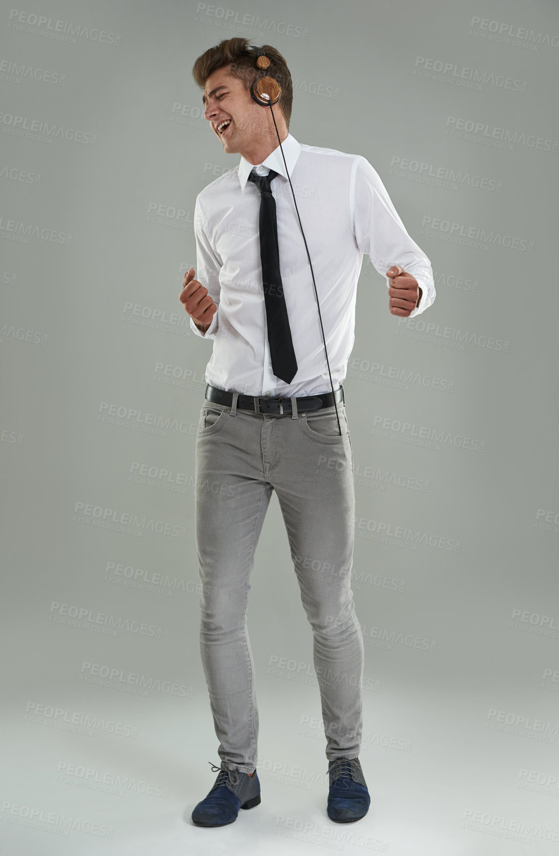 Buy stock photo A young man in a shirt and tie dancing while listening to music on his headphones