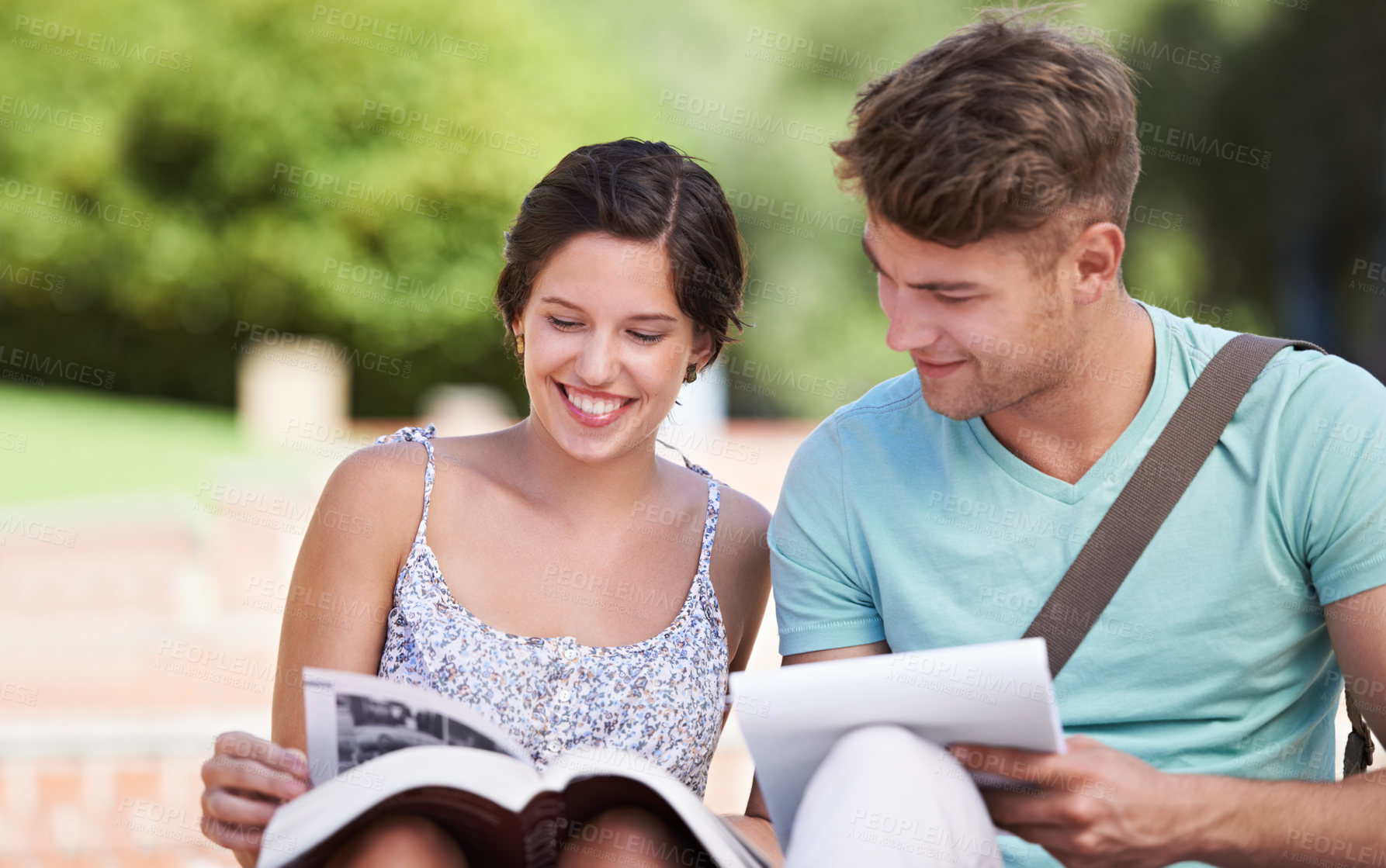 Buy stock photo A young couple in college sitting together and studying in the park