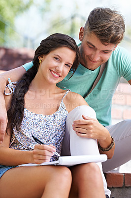 Buy stock photo A young couple studying together on the steps in the park