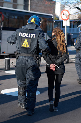 Buy stock photo Police man arrest woman at protest in city, crime and law enforcement, security at demonstration in the street. Public servant, service and patrol for safety at event, activist and officer back view