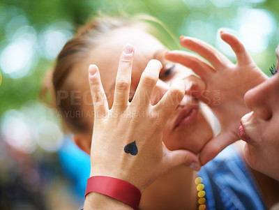 Buy stock photo Hands, lesbian couple and women with heart outdoor, bonding and fun at music festival. Closeup, sign and love of gay girls together for celebration with tattoo for care in nature on valentines day