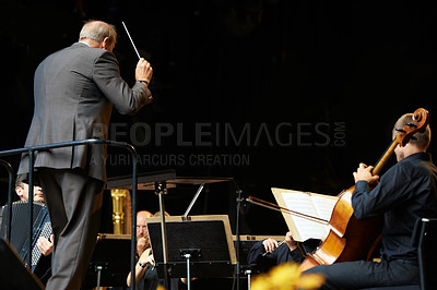 Buy stock photo Conductor, musicians and orchestra concert on stage or live music at festival for entertainment, performance or event. People, violin and playing instrument or symphony artist, behind or professional