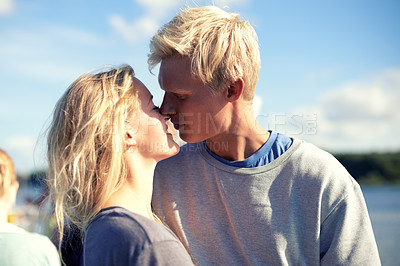 Buy stock photo Young romantic, couple kissing and outdoor for bonding to enjoy holiday together. Love, peace and calm relax feeling happy on date, vacation and travel at sunset on nature adventure or honeymoon