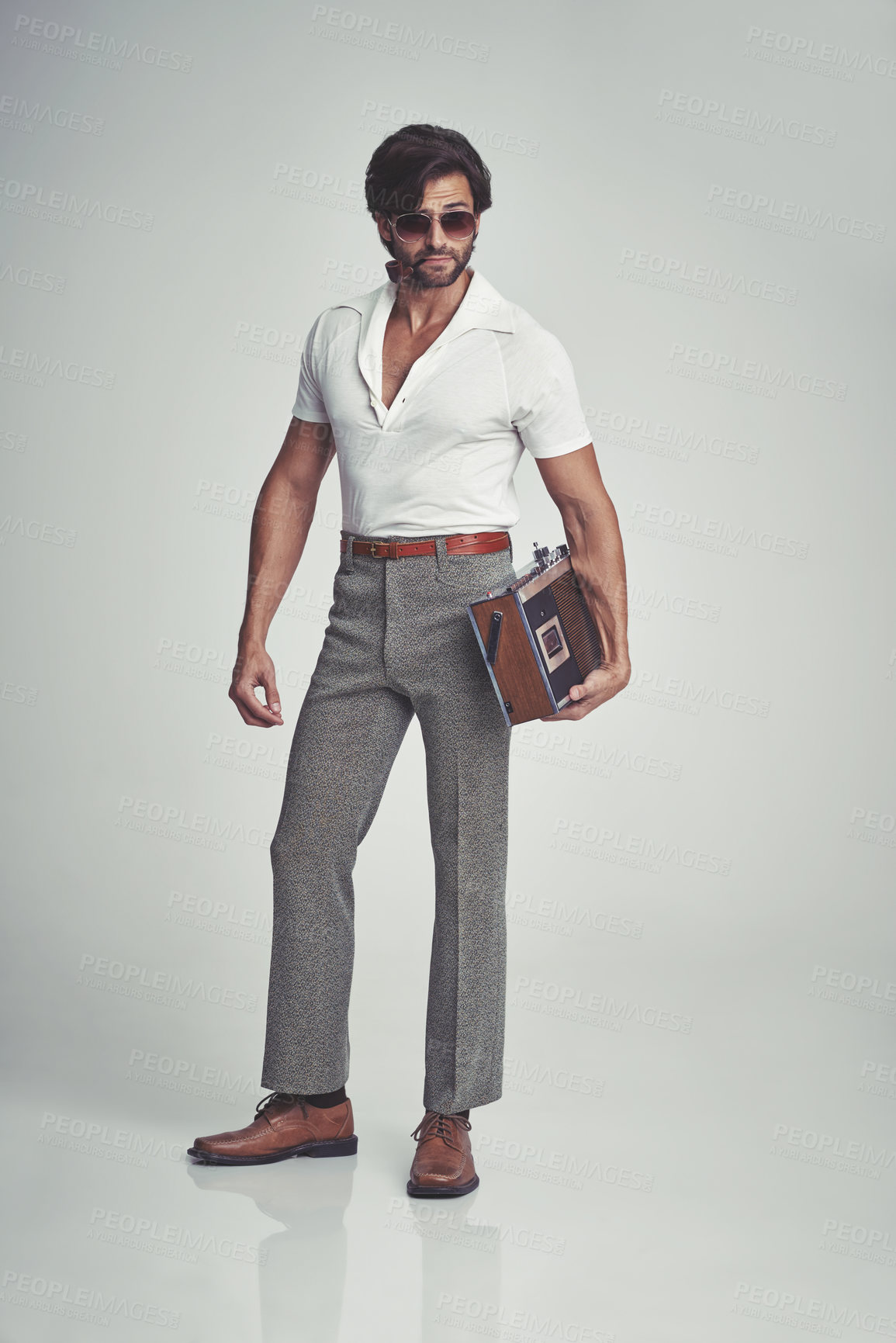 Buy stock photo A studio shot of a handsome man in retro 70s wear holding a cassette player