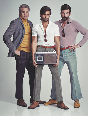 Buy stock photo A studio shot of three men clad in retro 70s wear holding a cassette player