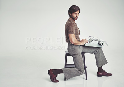 Buy stock photo Studio shot of a 70's style businessman sitting on a stool using a typewriter