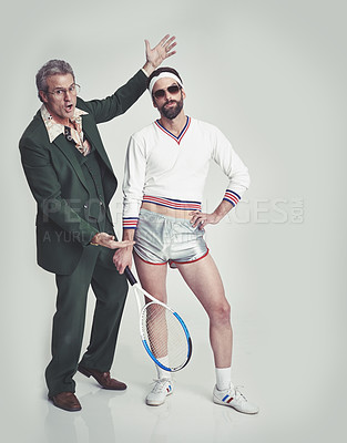 Buy stock photo A mature man in a retro suit trying to present a young man in retro tennis clothes