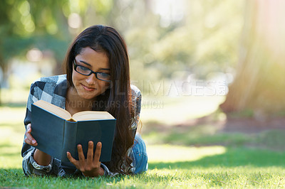 Buy stock photo Happy woman, student and reading at park with book for literature, studying or story in nature. Female person, smart or young adult with smile or glasses for chapter, learning or outdoor education