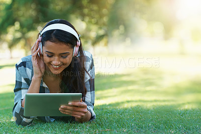 Buy stock photo Woman, headphones and streaming music on grass, radio and internet for podcast on tablet in outdoors. Female person, happy and relaxing on lawn, weekend playlist and subscription to movie or series