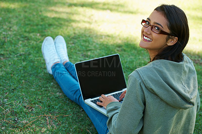 Buy stock photo A young woman working on her laptop in the park