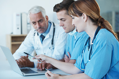Buy stock photo Shot of three medical professionals having a discussion over a laptop