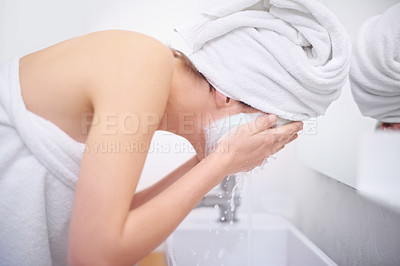 Buy stock photo A young woman washing off her facial mask in her bathroom