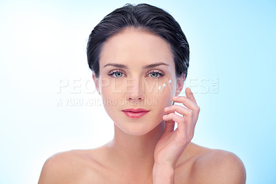 Buy stock photo Woman, portrait and moisturizer application or cream for smooth skincare for treatment, dermatology or wellness. Female person, face and lotion on blue background in studio, mockup space or product