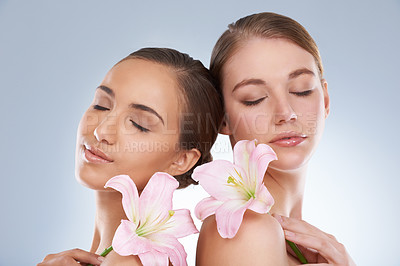 Buy stock photo Woman, relax and skincare with flowers for natural beauty, makeup or cosmetics on a blue studio background. Young female, people or models smile in satisfaction for spa, soft skin or facial treatment