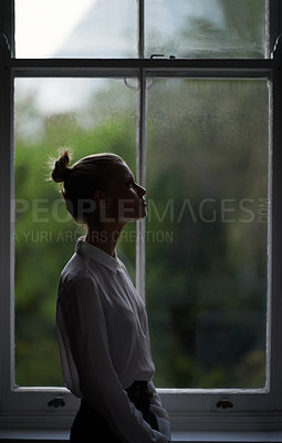 Buy stock photo A beautiful young woman standing by a window
