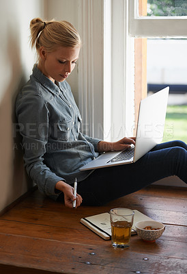 Buy stock photo A young woman sitting on a floor doing some researching on her laptop