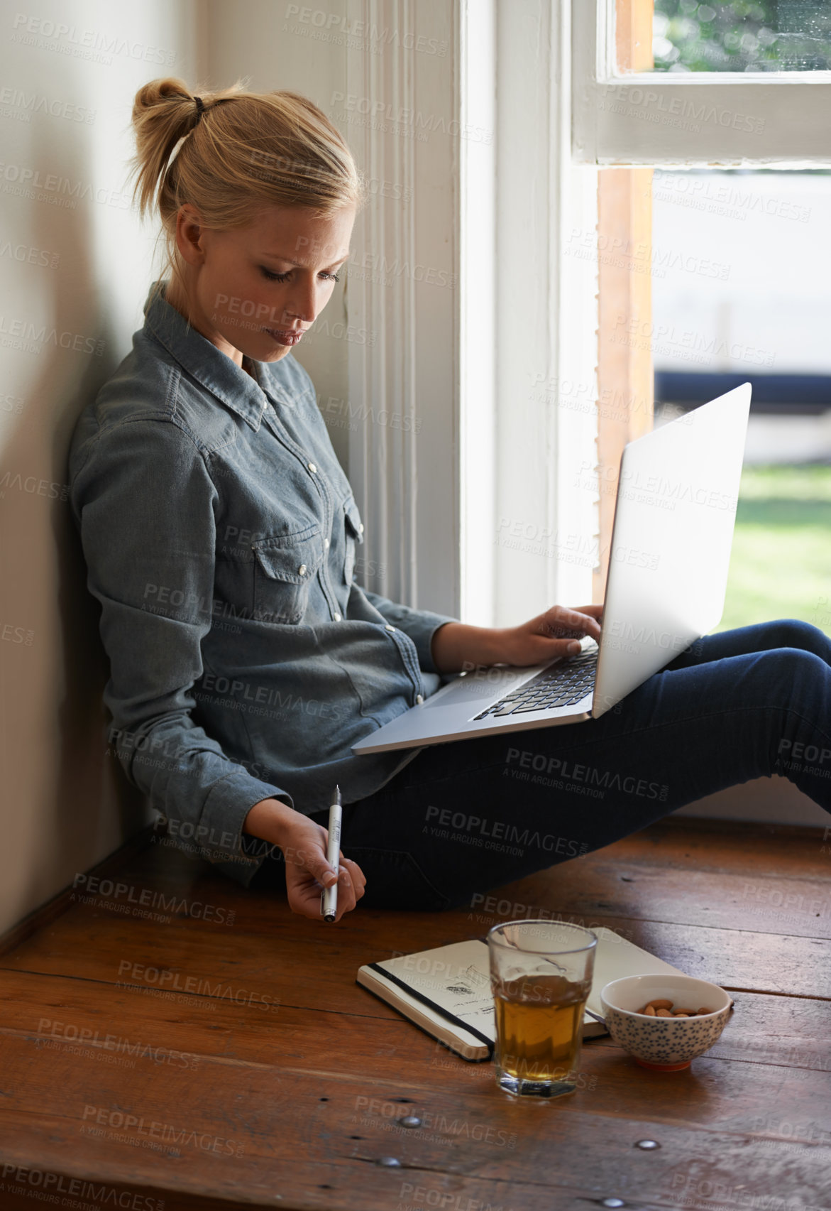 Buy stock photo A young woman sitting on a floor doing some researching on her laptop