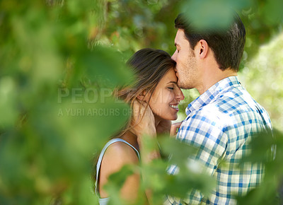 Buy stock photo Portrait, young couple and kissing under the trees in the park and enjoying love in the summer sun. Cheerful, special and outdoor proposal, romantic partners bonding loving and playful lifestyle