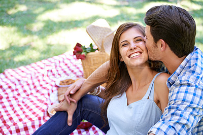 Buy stock photo Love, picnic and happy couple kiss in park for summer holiday and bonding in nature. Getaway, vacation and man and woman with romance and affection with food for garden, relationship and date