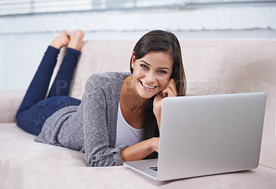 Buy stock photo A young woman relaxing on the couch with a laptop and cellphone