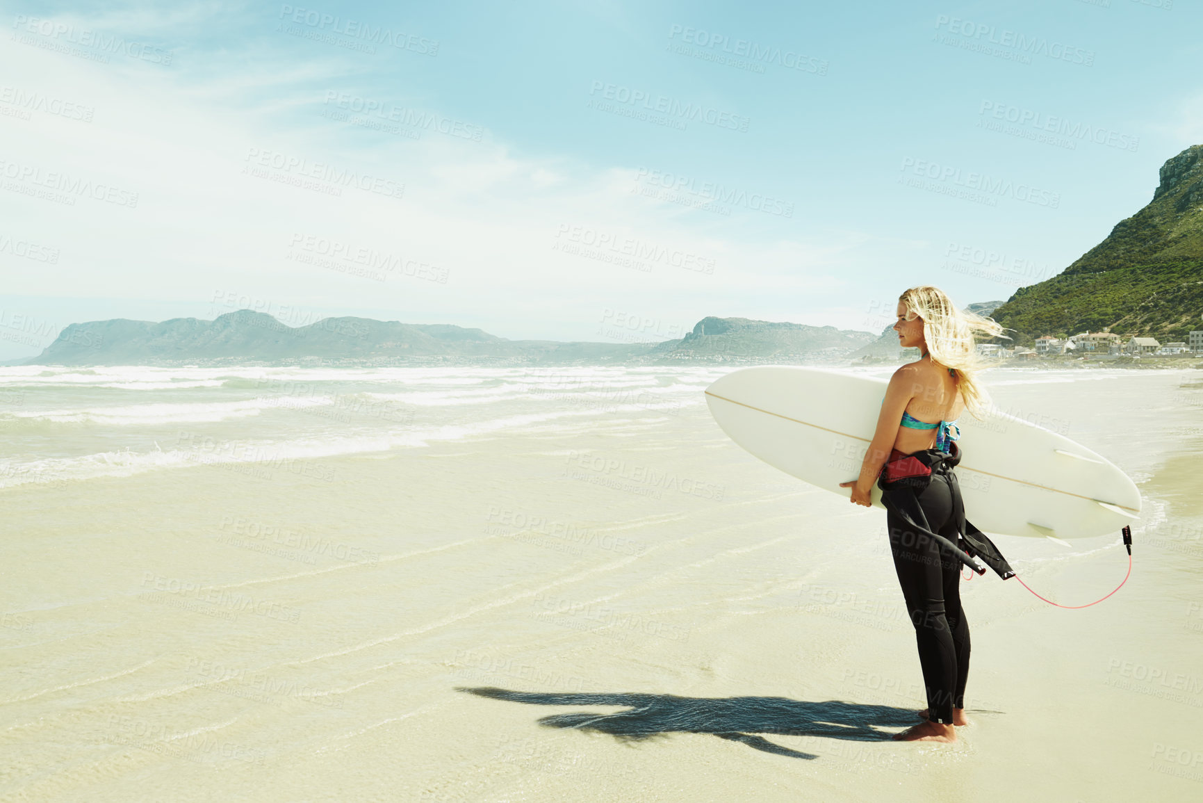 Buy stock photo A young female surfer holding her surfboard while standing on a beach