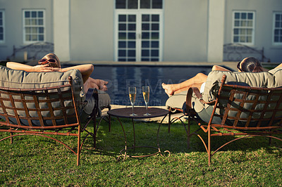 Buy stock photo Rear view of two young woman relaxing on loungers facing the pool