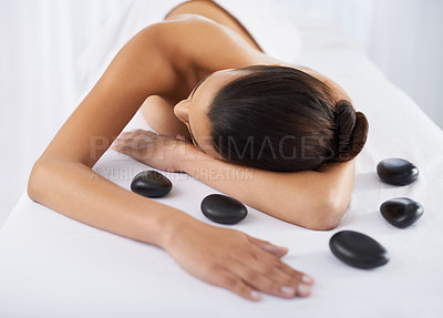 Buy stock photo Hot stone, spa and massage table for wellness in luxury and health with skin, salon and oil. Woman, self care and relax at resort for stress relief, zen and satisfaction for beauty and wellbeing